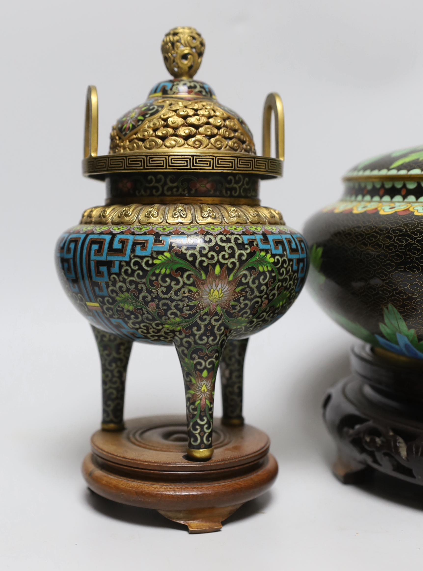 A Chinese cloisonné enamel three footed vase and cover together with a censer and cover, each raised on hardwood stands, the largest 26cm in diameter